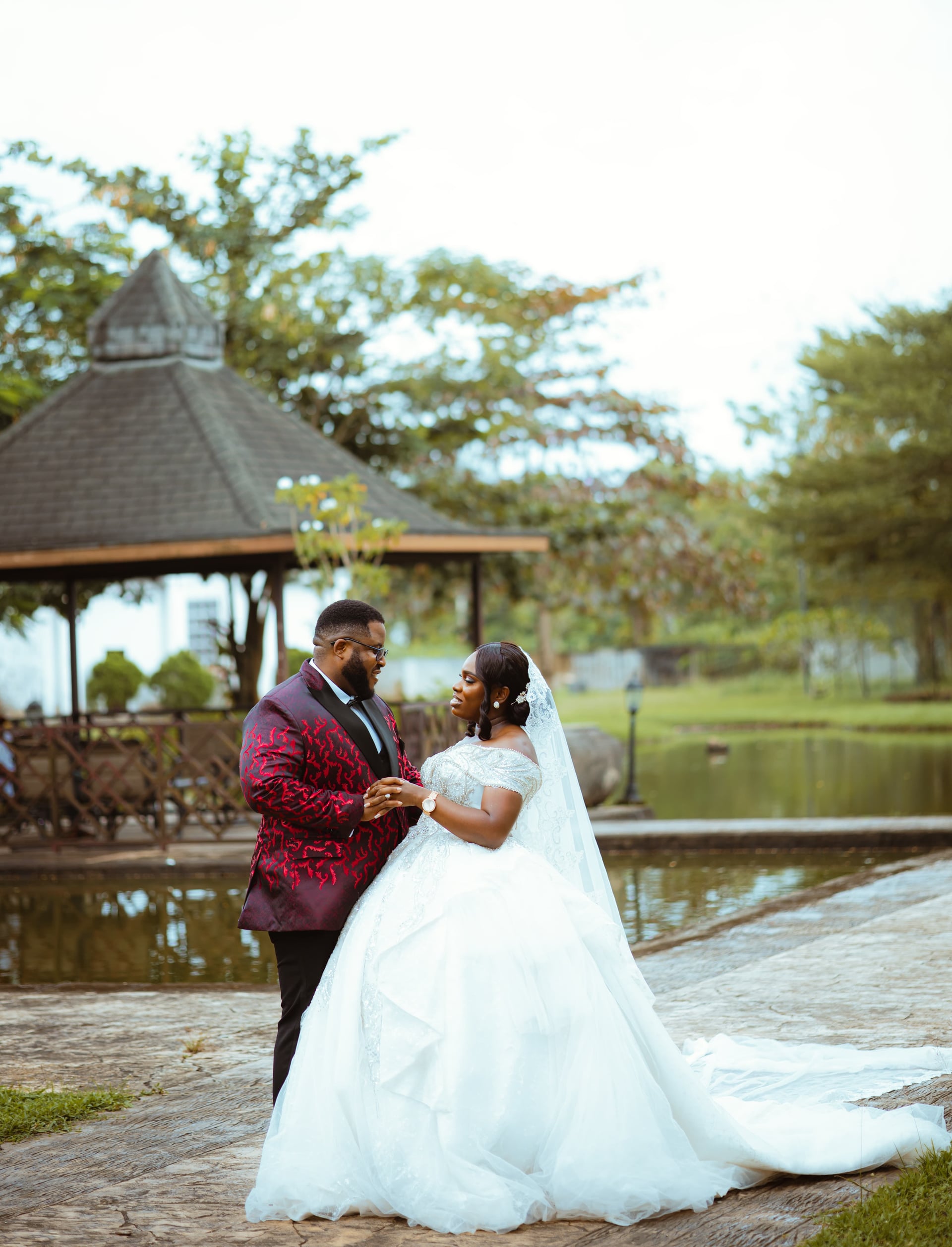 A bride and groom dancing beside a pond and pavilion